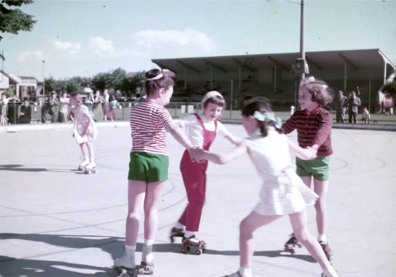 Children on roller skates hold hands in circle on track